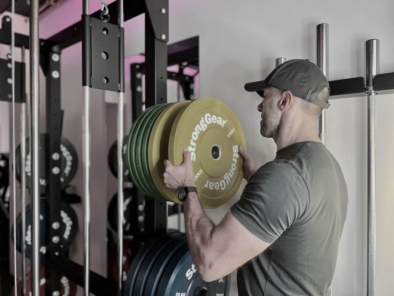 Person at Solospace Gym returning weight plates to the rack, cleaning up equipment at the end of their workout session